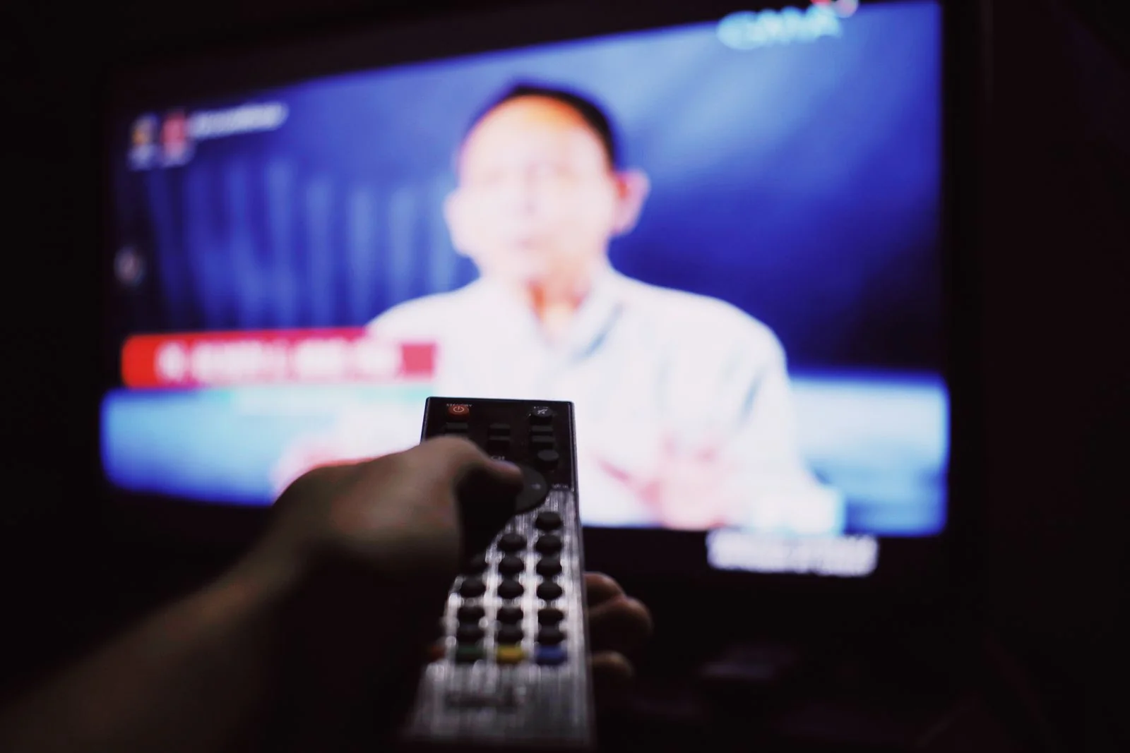Fotografía de referencia: Uso de un control remoto frente a una pantalla de televisión.